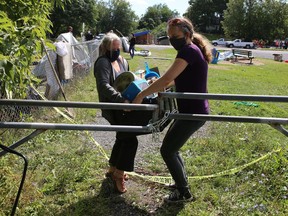 Homeless advocates carry out belongings of Belle Park residents as the city closed down the encampment in Kingston on Tuesday. (Elliot Ferguson/The Whig-Standard)