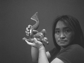 A studio portrait of Oviloo Tunnillie with one of her sculptures in November 1980 in Cape Dorset, Nunavut. (Judith Eglinton/Library and Archives Canada)