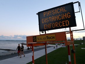 A sign in place Friday evening at Breakwater Park informs visitors that physical distancing is being enforced at the downtown Kingston park. (Ian MacAlpine/The Whig-Standard)