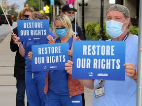 Hospital support workers, including housekeeping workers Stewart Barr, front, and Toni Bonnett of Hotel Dieu Hospital and other members of CUPE 1974, picket outside Hotel Dieu Hospital and Kingston General Hospital against Bill 195 on Tuesday. (Ian MacAlpine/The Whig-Standard)