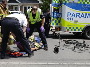 Frontenac County paramedics and Kingston firefighters tend to a cyclist injured in a collision in Kingston. (Elliot Ferguson/The Whig-Standard)