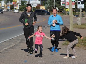 Five-year-old Katelyn D'Silva receives a supportive high-five from cousin Elysa MacDougall as she runs down Pembroke Street East and prepares to turn onto Rankin Street. Also in the photo are Dave Symons, left, and Kelly MacDougall, Katelyn's mom. Anthony Dixon