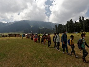 Children, who miss their online classes due to lack of internet facility, walk in a line as they leave after attending their open-air classes after schools were closed following the COVID-19 outbreak, in central Kashmir's Budgam district on Aug. 24. (Danish Ismail/Reuters)