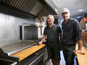 Gus Papadakos, left, and his son George Papadakos, stand near the grill where 'the magic happened' at Corey's Restaurant. After 35 years operating a successful family restaurant in Tillsonburg, Gus is retiring. Last Wednesday George announced the building has been sold and the restaurant is closing. (Chris Abbott/Norfolk Tillsonburg News)