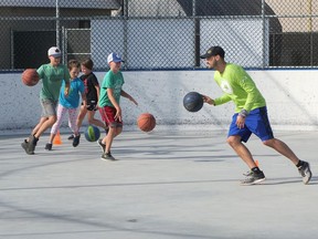 Mark Salt, right, Recreation Programs Supervisor in Tillsonburg, leads a group of kids in a summer basketball drill at the J.L. Scott McLean Outdoor Recreation Pad. (Chris Abbott/Norfolk Tillsonburg News)