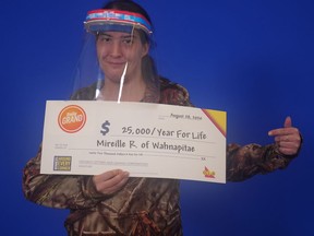 Wearing her PPE, Mireille (Mimi) Roy of Wahnapitae picks up her Daily Grand win at the OLG Prize Centre in Toronto. Supplied photo