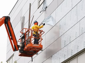 A worker removes protective coating off panels installed on the education building at Laurentian University in Sudbury, Ont. on Tuesday September 15, 2020.