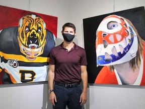Michael Slotwinski can be found in this photo alongside paintings from his series of portraits of famous and less famous NHL net-minders, illustrating the evolution of hockey masks.
