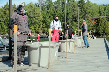 Masked anglers wait two metres apart during second day weigh-ins of the 24th annual Bassin' For Bucks fishing tournament in Sioux Narrows on Saturday, Sept. 12.