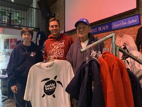 From left: graphic designer Kelsey Mason, marketing manager Jordan Spencer and founder of Turtle Beach Clothing Bob Firth show off some of their collection at Bob's Burgers on Main Street.