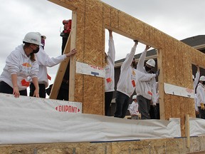 Students in the Building Futures program ensure the first wall to go up on the house they are building is in place on Thursday, Oct. 9 at the construction site of a duplex near Copperhaven School.