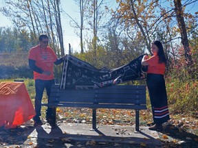 A bench and plaque are unveiled near Bear Creek by 99 Avenue in Grande Prairie, Alta. during Orange Shirt Day on Wednesday, Sept. 30, 2020. The plaque and bench will honour those impacted by residential schools.