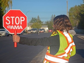 Grade 6 student Emma Peterson holds a stop sign to allow pedestrians to cross 88 Avenue and safely reach École St. Gerard School in Grande Prairie, Alta. on Tuesday, Sept. 3, 2019.