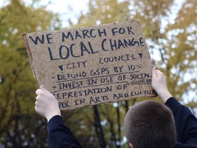 A protester holds a sign calling for changes to police funding and better representation on arts and culture groups during a rally Sunday in downtown Sudbury.