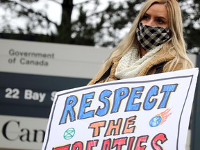 Demonstrators rally in support of Mi'kmaq fishermen in downtown Sault Ste. Marie, Ont., on Wednesday, Oct. 21, 2020. Sandra Holmberg holds sign outside federal government office building.  (BRIAN KELLY/THE SAULT STAR/POSTMEDIA NETWORK)