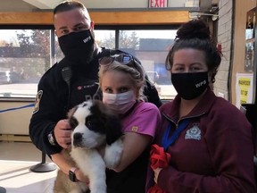 Benny the St. Bernard was reunited with his family by Woodstock police after being 'dognapped' on Oct. 17. Pictured, Woodstock police Cst. McMillan, who located the pup (left) with Woodstock police staff and Benny's owner (centre). (Woodstock Police Service)