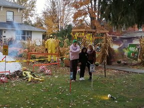 Leeanna Newton, right, is shown with her sons Mikyle, left, and Aydin, centre, outside of their home with an alien- and COVID-19-themed display. (Handout/Postmedia Network)
