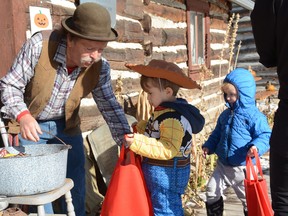 Kootenai Brown Pioneer Village's Farley Wuth hands candy out to Odin and Casey Shenton at the 2019 Halloween at the Village.