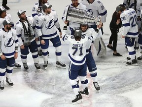 Tampa Bay Lightning's Anthony Cirelli hands off the Stanley Cup to Mikhail Sergachev.