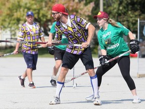 Fred Belanger, left, of Grapes' Grinders protects the ball from Tilbury Trailhawks' Chelsey Stevenson during a Chatham-Kent Road Hockey League game at the Chatham Memorial Arena parking lot in Chatham, Ont., on Sunday, Sept. 27, 2020. Mark Malone/Chatham Daily News/Postmedia