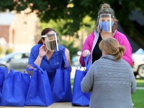 Kelly Ladd, right, and Sarah Regnier give out meals during the annual Entegrus Thanksgiving luncheon outside the Spirit & Life Centre in Chatham, Ont., on Friday, Oct. 9, 2020. (Mark Malone/Chatham Daily News)