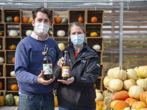 Tom Heeman holds a bottle of Dry Empire Hard Apple Cider and his wife Susan Judd holds a bottle of Dutch Crumble Hard Apple Cider that are made at Heeman's Garden Centre and Strawberry Farm in Thorndale. (Derek Ruttan/The London Free Press)