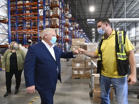 Ontario Premier Doug Ford, left, fist bumps an employee as he tours a warehouse where they ship personal protective equipment during the COVID-19 pandemic in Milton. Thursday, Ford announced effective Oct. 1 Ontario will pay $2 to $3 an hour more in wages to an estimated 147,000 personal support workers needed to care for hospital patients, seniors and children in congregate care settings. 
CANADIAN PRESS