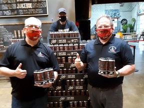 Br. 642 Royal Canadian Legion Pipe Band members Brent Flaglor, left, and Tom Elliott, right, are pictured with Doug Hunter, a partner in Sons of Kent Brewery, holding some six-packs from the second batch of Fingask '45 red ale that's been made by the local brewery to help raise funds for the band, which has been idle during the COVID-19 pandemic. (Handout)