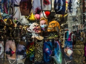 Geoff Waszek, owner of Candy's Costume Shop, 685 Mt. Pleasant Rd. is seen through the front window and hanging face masks at his store in Toronto, Ont. on Thursday October 15, 2020.