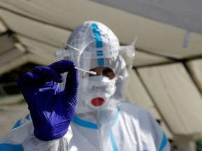 A medical staff member wearing a protective suit holds a swab as he waits for people who will be tested for the coronavirus disease at a newly opened drive-in sampling station in Prague, Czech Republic, October 7, 2020.