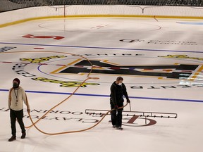 JJ Straker, right, Leon's Centre's  director of facility services spreads water on the ice surface in preparation to opening the facility to user groups with Rob Moeys, manager operations on Monday October 26, 2020.