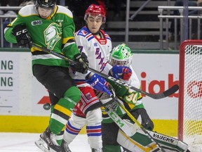 Knights forward Connor McMichael gets hit by the puck as he checks Kitchener's Mike Petizian in front of goalie Brett Brochu during a game last February at Budweiser Gardens in London. McMichael and Brochu are among the 47 players invited to try out for the Canadian world junior team. (Mike Hensen/The London Free Press)