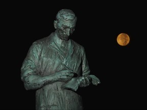 The Frederick Banting statue outside the Banting House museum is lit by the moon on Adelaide Street in London. (File photo)