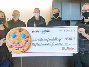 Bernadette Lindsay, fund development co-ordinator with Nipissing Serenity Hospice, and Gil Pharand, executive director of the hospice, hold a cheque showing the total local sales of Tim Hortons Smile Cookies, while local Tim Hortons franchise owners Derek Bobowski, Ken Coughlin, and Brandon Moffat participate in the ceremony.Submitted Photo