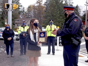 Katlyn Van Horn, 17, is presented with a plaque from the North Bay Police Service, Thursday, recognizing her efforts to get traffic lights installed at Highway 94 and Callander Bay Drive. Michael Lee/The Nugget