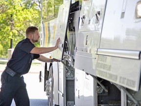 Motor coach operator Austin Talbot closes the baggage doors to a motor coach in North Bay. Ontario Northland Photo