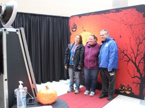 Angel Graham, left, Stacy Boyd and Dan Robar pose for a photo at the "open-air" photo booth in Lambton Mall Thursday. The booth can be used for photos for a Halloween costume contest the mall has underway, a mall official said. (Paul Morden/The Observer)