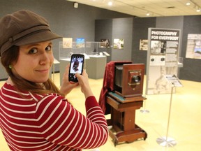 Dana Thorne, curator-supervisor of the Lambton Heritage Museum, is pictured in December 2019 snapping a photo of the exhibit, Capturing the Moment: Photography in Lambton County. The exhibit reopens to the public Wednesday. (Paul Morden/Sarnia Observer)