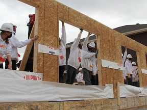 Students in the Building Futures program ensure the first wall to go up on the house they are building is in place on Thursday, Oct 9 at the construction site of a duplex near Copperhaven School.