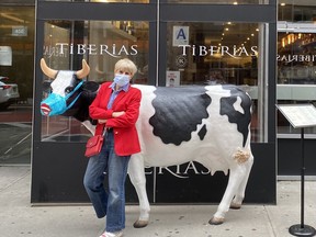 Author Bonnie Kogos 'moo'ves around New York City, posing beside a bovine with facial covering outside a restaurant.