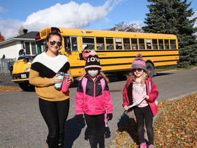 Ashley Savard-Sikatowsky greets her kids, Comia, 7, middle, and Aubrie, 6, at the school bus drop-off location near their home  on Thursday.