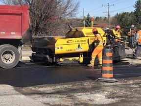 A paving crew lays down an initial coat of asphalt.