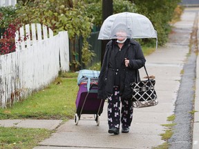 A woman attempts to keep dry while walking in the rain in Sudbury, Ont. on Friday October 23, 2020. Environment Canada said Greater Sudbury can expect a mix of sun and cloud with a high of 4 C on Saturday. John Lappa/Sudbury Star/Postmedia Network