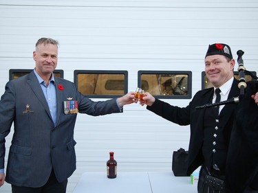 Daryl Adams, left, a veteran and co-founder of  RufDiamond Ltd., and piper John Macdonald, of the Greater Sudbury Police Pipe Band, take part in a toast called "Paying the Piper", after a massive Remembrance Day flag featuring a poppy and Lest We Forget, was raised to show support for veterans and current serving members of the Canadian Armed Forces at a ceremony in Sudbury, Ont. on Friday October 30, 2020. "The intent of this initiative is to bring awareness to the Poppy Campaign. Many people are unaware that the national launch is always the last Friday in October," said  Adams. The flag is located in New Sudbury behind the MIC restaurant. The event was supported by Lopes, Coniston Industrial Park and IAMGOLD Corporation. John Lappa/Sudbury Star/Postmedia Network