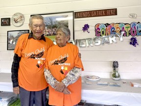 Cecil, left, and Delores Isaac at their 70th wedding anniversary on Sept. 30. Behind them is a picture of the 72-person family that all started with the couple. (Jake Romphf, Postmedia Network)