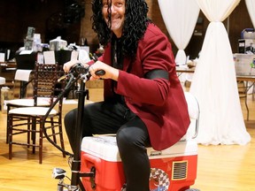 Bewigged auctioneer Greg Hetherington takes a spin on a Cruzin Cooler from the Festival of Giving auction at the Chatham Armoury on Oct. 17. Mark Malone/Postmedia Network