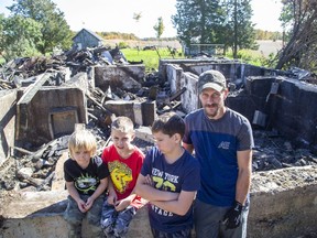 Justin Whitney with three of his six children, J.D., 3, Trent, 7, and Kayden, 10, visit the site of their former home, which was destroyed by fire in Dutton. Derek Ruttan/Postmedia Network