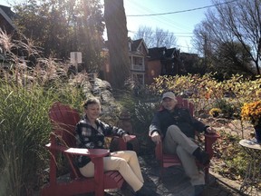 On the front patio, the tall grasses provide privacy while John and Maureen relax in red Adirondack chairs.