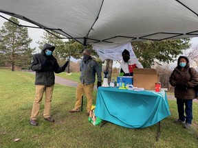 Lucky Ikhuebor, left, speaks at a migrant rights event on Sunday in Bell Park. Listening are Scott Florence and Demarie Bahjean of the Sudbury Workers Education and Advocacy Centre, along with Haja Lucien.