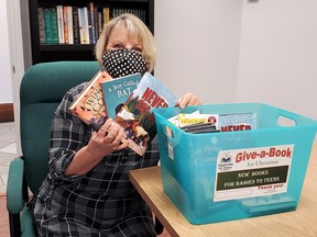 The Organization for Literacy in Lambton’s Rosemary Travis holds up books already donated to the agency’s annual Give-a-Book Christmas campaign, which runs until Dec. 1. Carl Hnatyshyn/Sarnia This Week